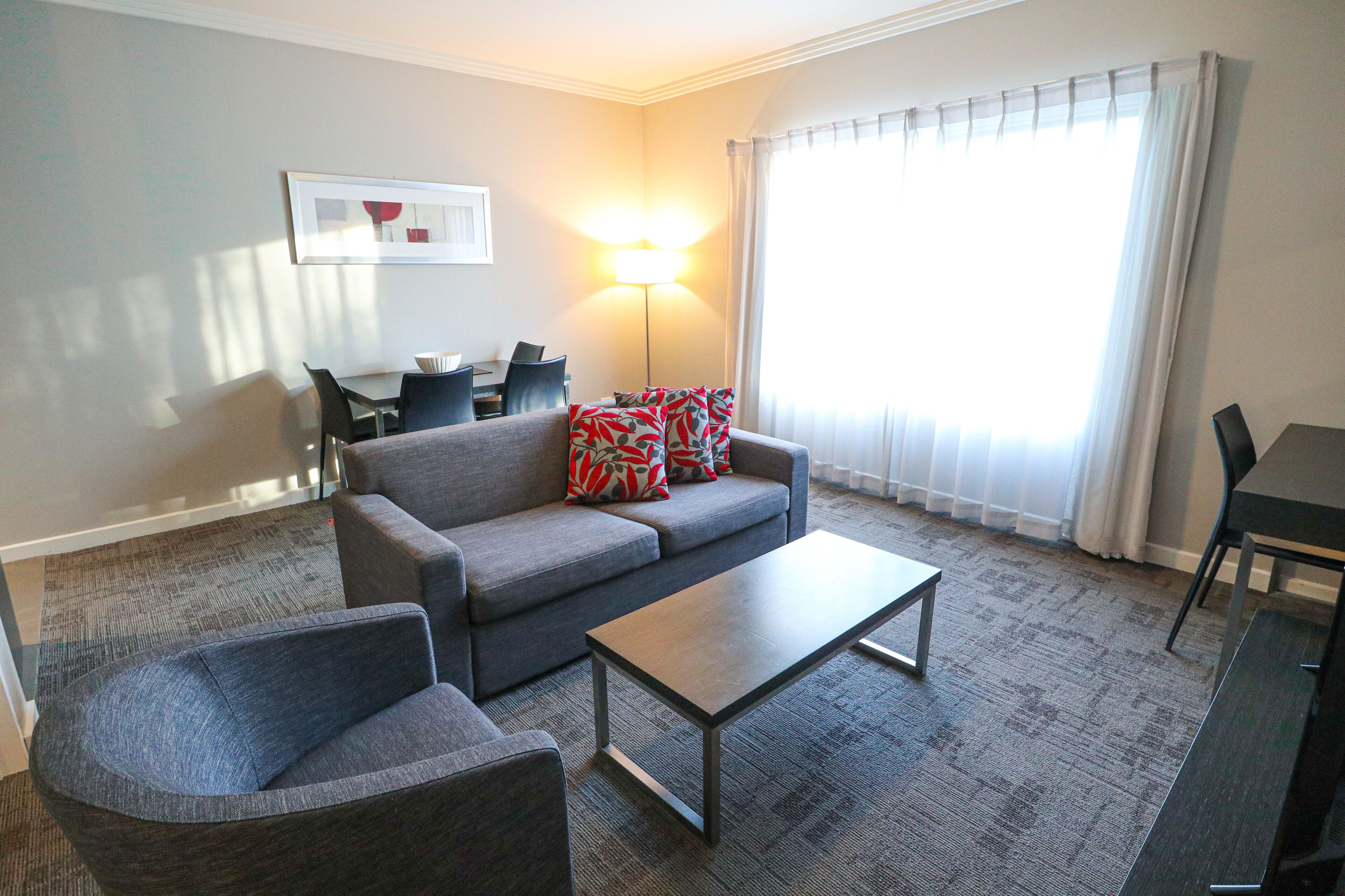 A living room with a grey sofa, a coffee table, and a dining table with chairs.