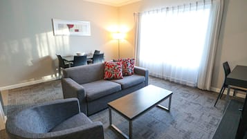 A living room with a grey sofa, a coffee table, and a dining table with chairs.