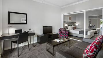 A modern hotel room with a desk, TV, and a sofa.