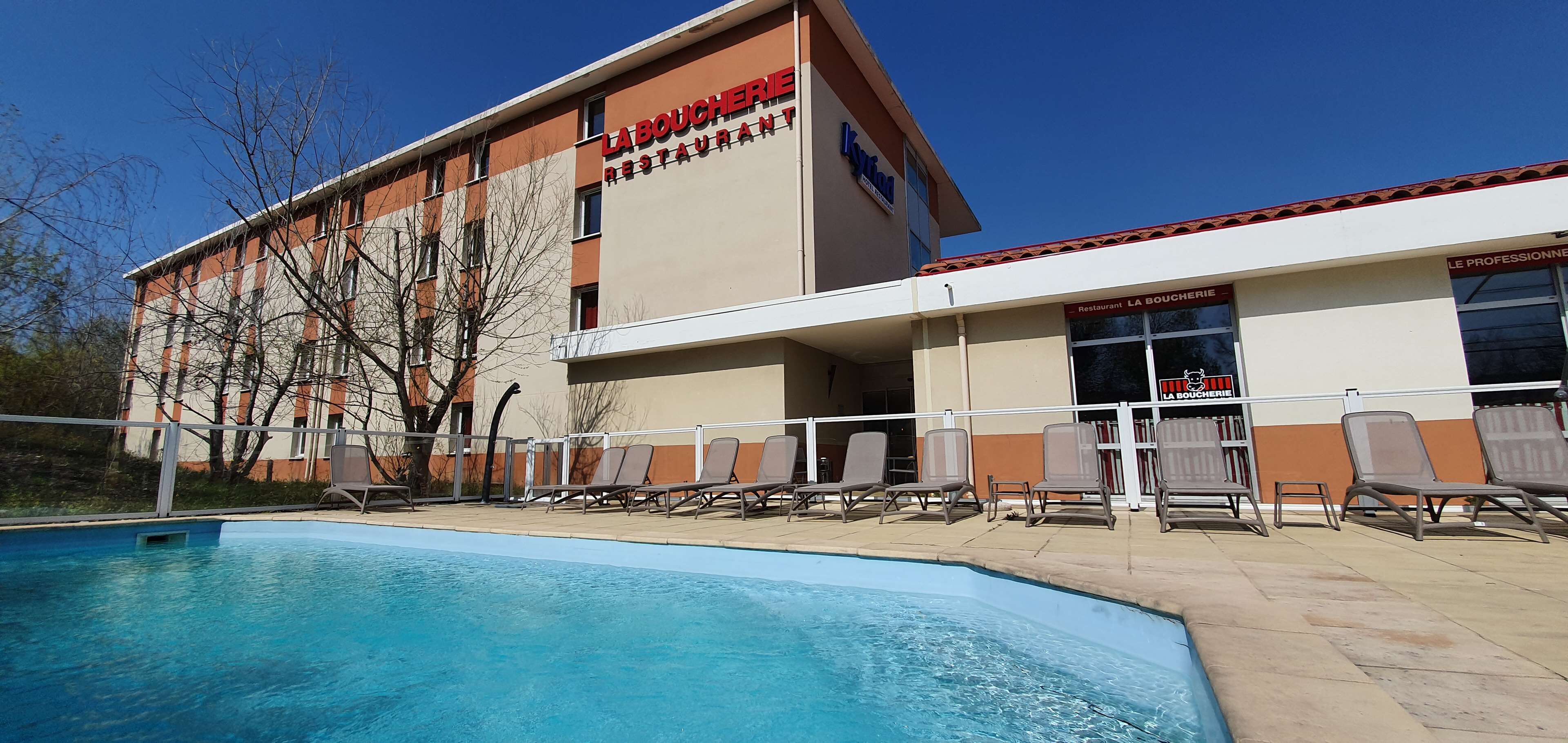 A building with a swimming pool and lounge chairs.