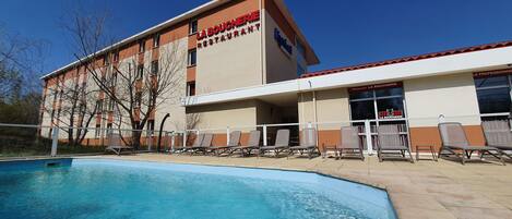 A building with a swimming pool and lounge chairs.