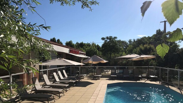 A poolside area with lounge chairs and umbrellas, a clear blue pool, and a restaurant named "LA BOUCHERIE" in the background.