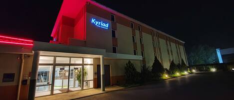 Un hotel con un letrero llamativo que dice "Kyriad Hotel Restaurant".