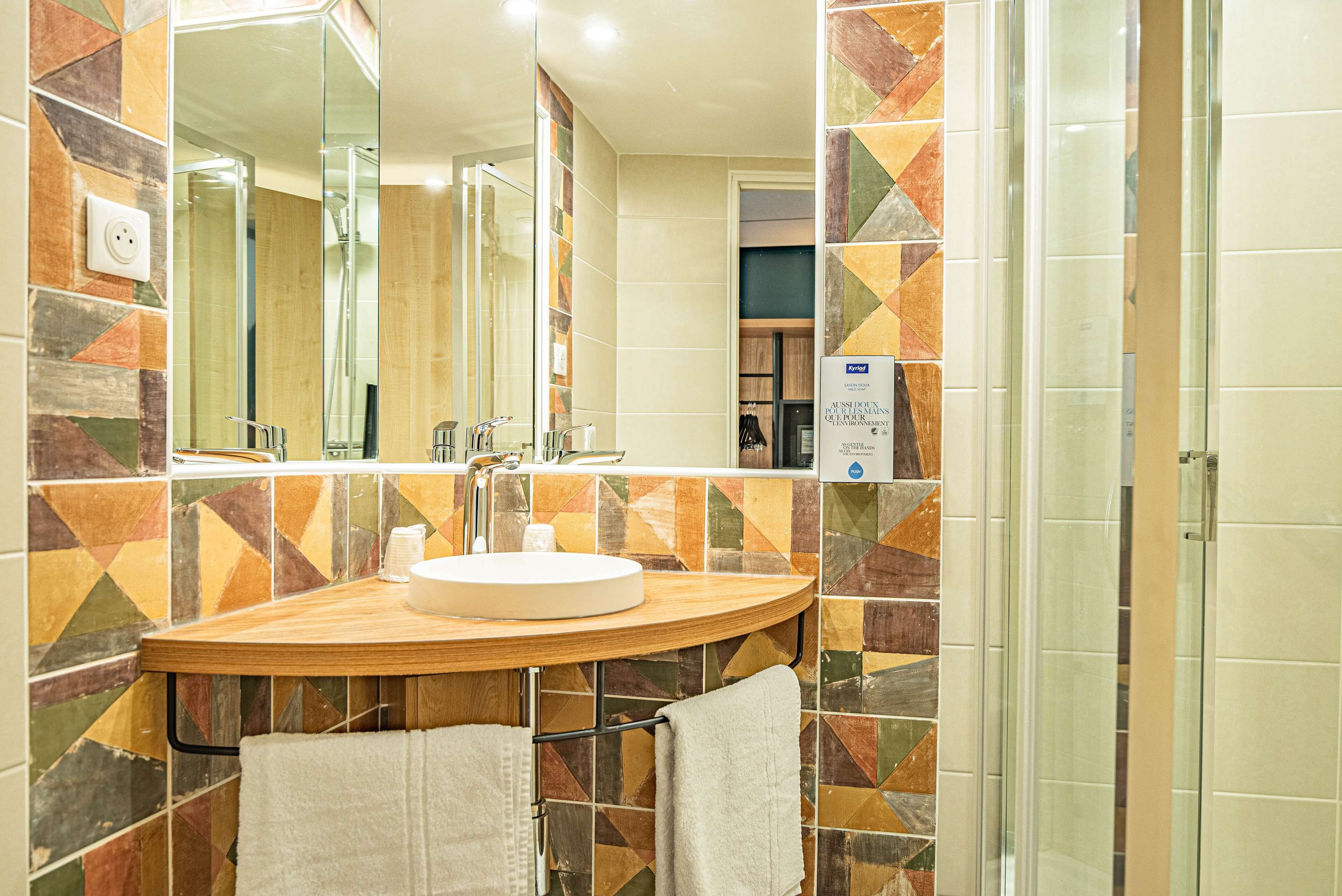 A bathroom with a wooden vanity, a round sink, and a mirror.