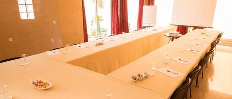 Una sala de conferencias con una larga mesa, sillas, una pizarra y un ventanal con cortinas.