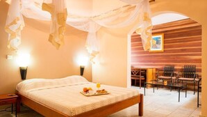 Un dormitorio con cama con dosel, una bandeja de desayuno y una zona de estar con sillas y una mesa.