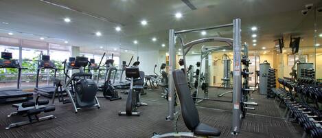 A gym with various exercise equipment, including treadmills, weight machines, and free weights.