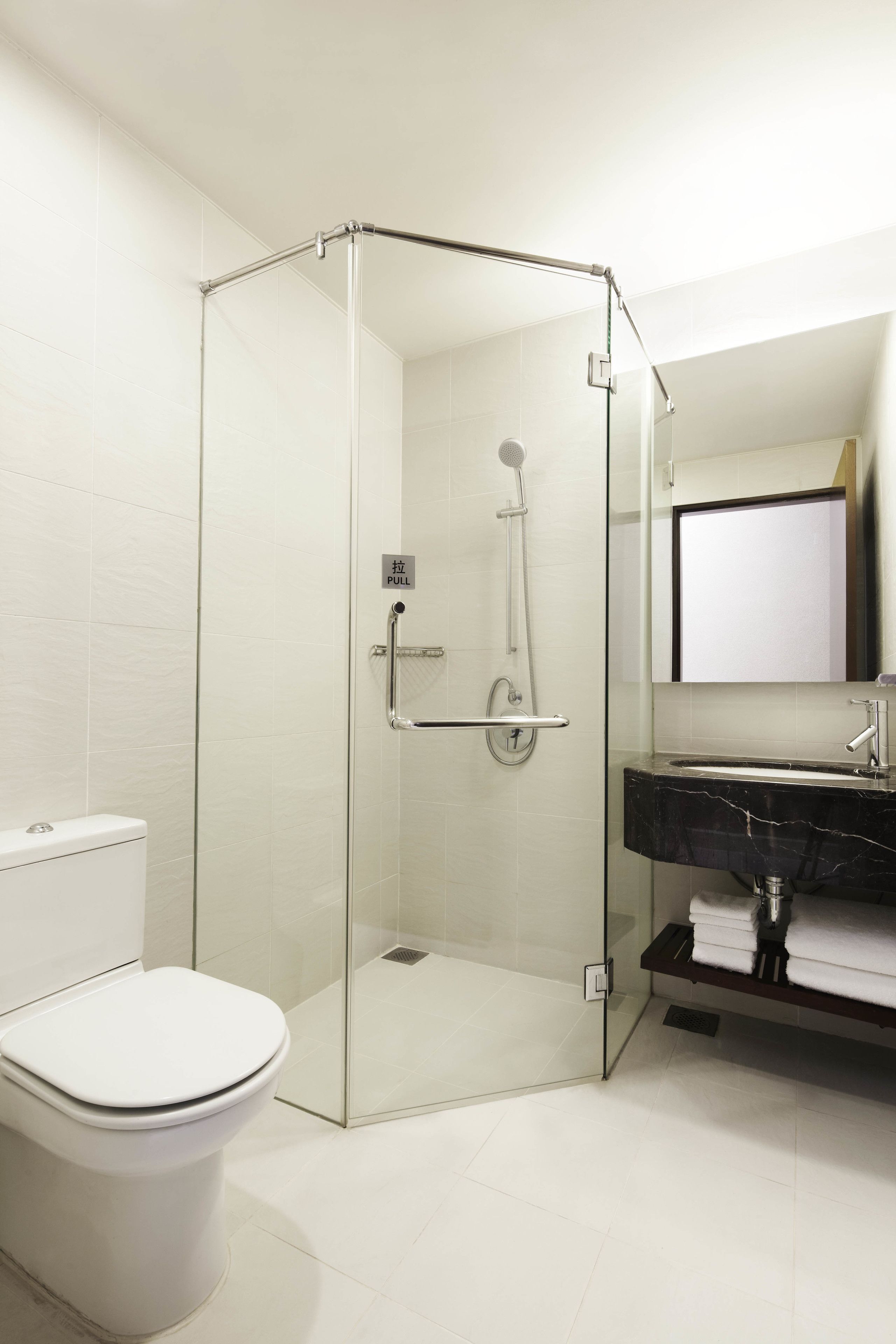 A modern bathroom with a glass-enclosed shower, a white toilet, and a black marble sink.