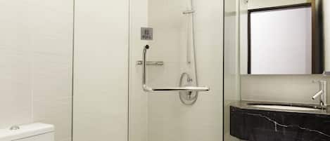 A modern bathroom with a glass-enclosed shower, a white toilet, and a black marble sink.