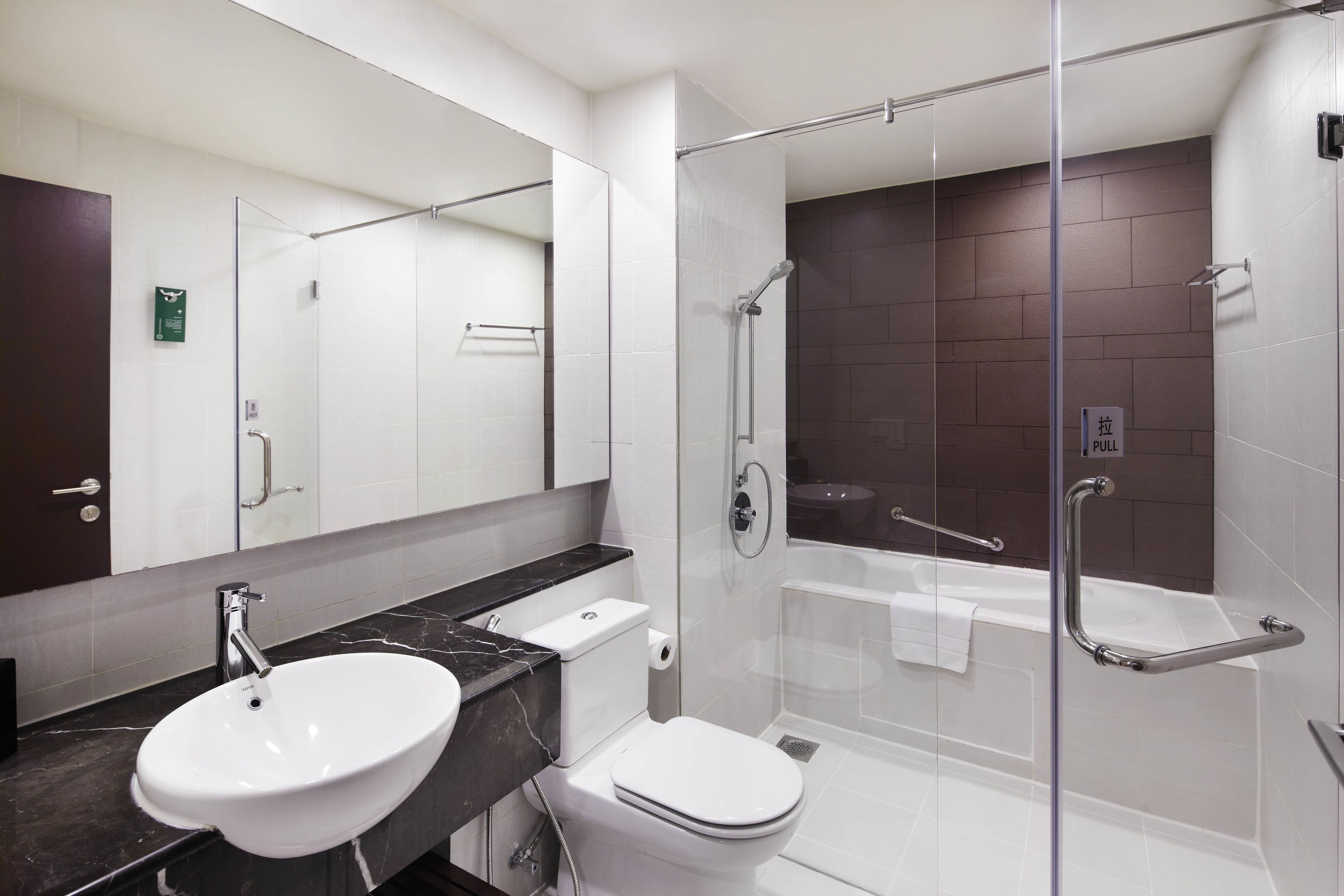 A modern bathroom with a glass-enclosed shower, a white sink, and a toilet.