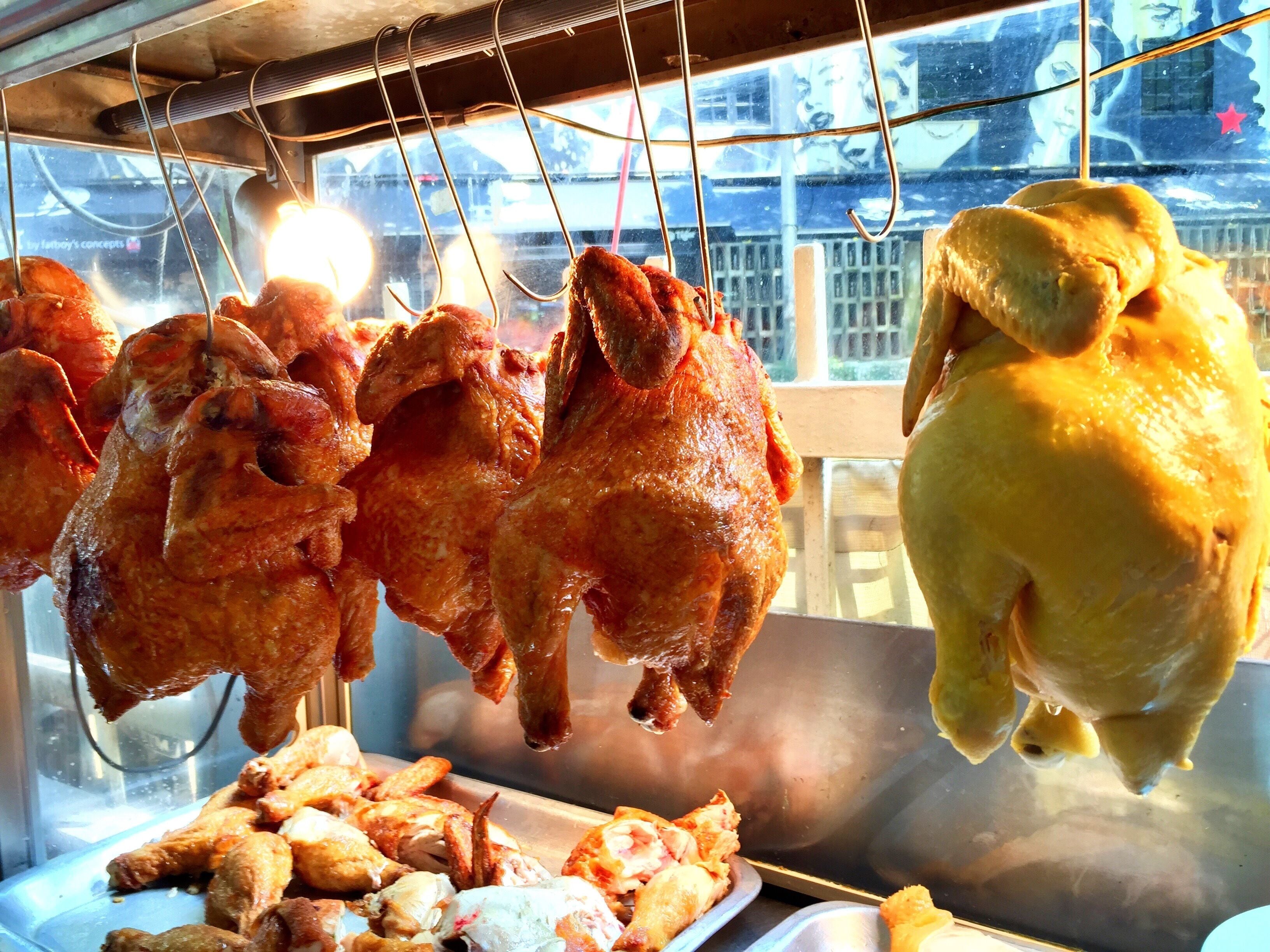 A display of roasted chickens hanging in a kitchen.