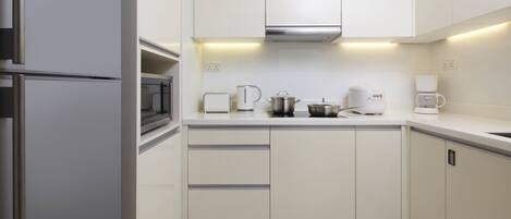 A modern kitchen with white cabinets, stainless steel appliances, and a built-in oven.