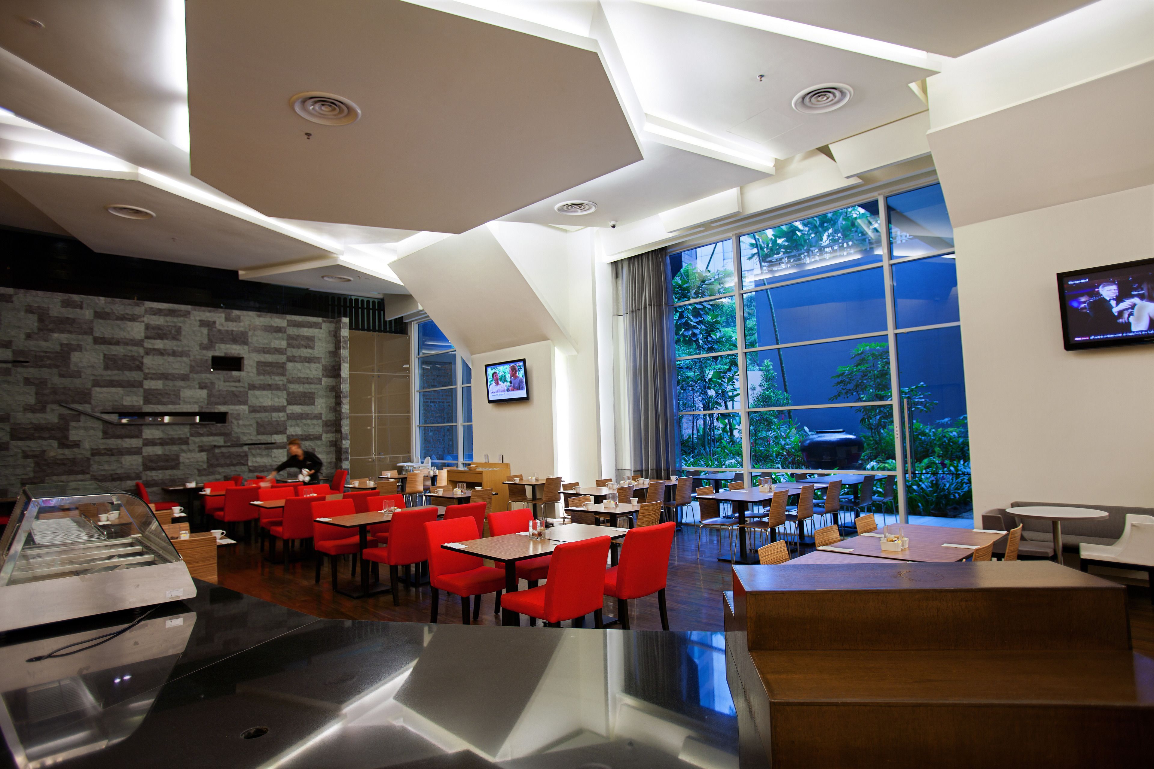 A modern restaurant with high ceilings, large windows, and a variety of seating arrangements including tables and chairs.
