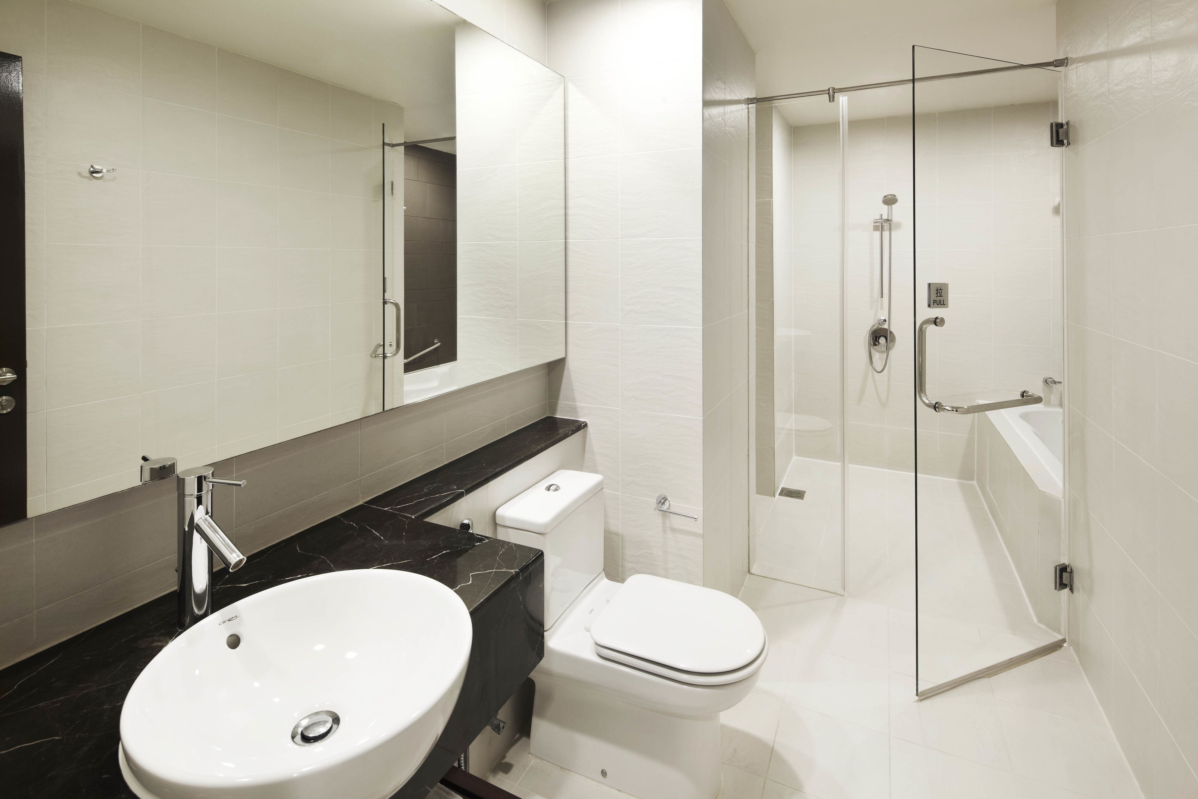 A modern bathroom with a white sink, toilet, and glass-enclosed shower.