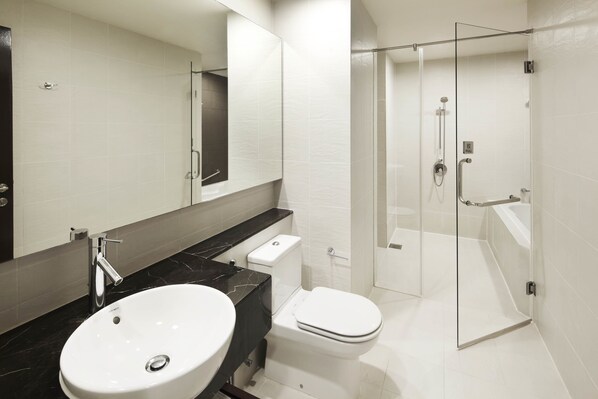 A modern bathroom with a white sink, toilet, and glass-enclosed shower. - PARKROYAL Serviced Suites Kuala Lumpur (Kuala Lumpur)