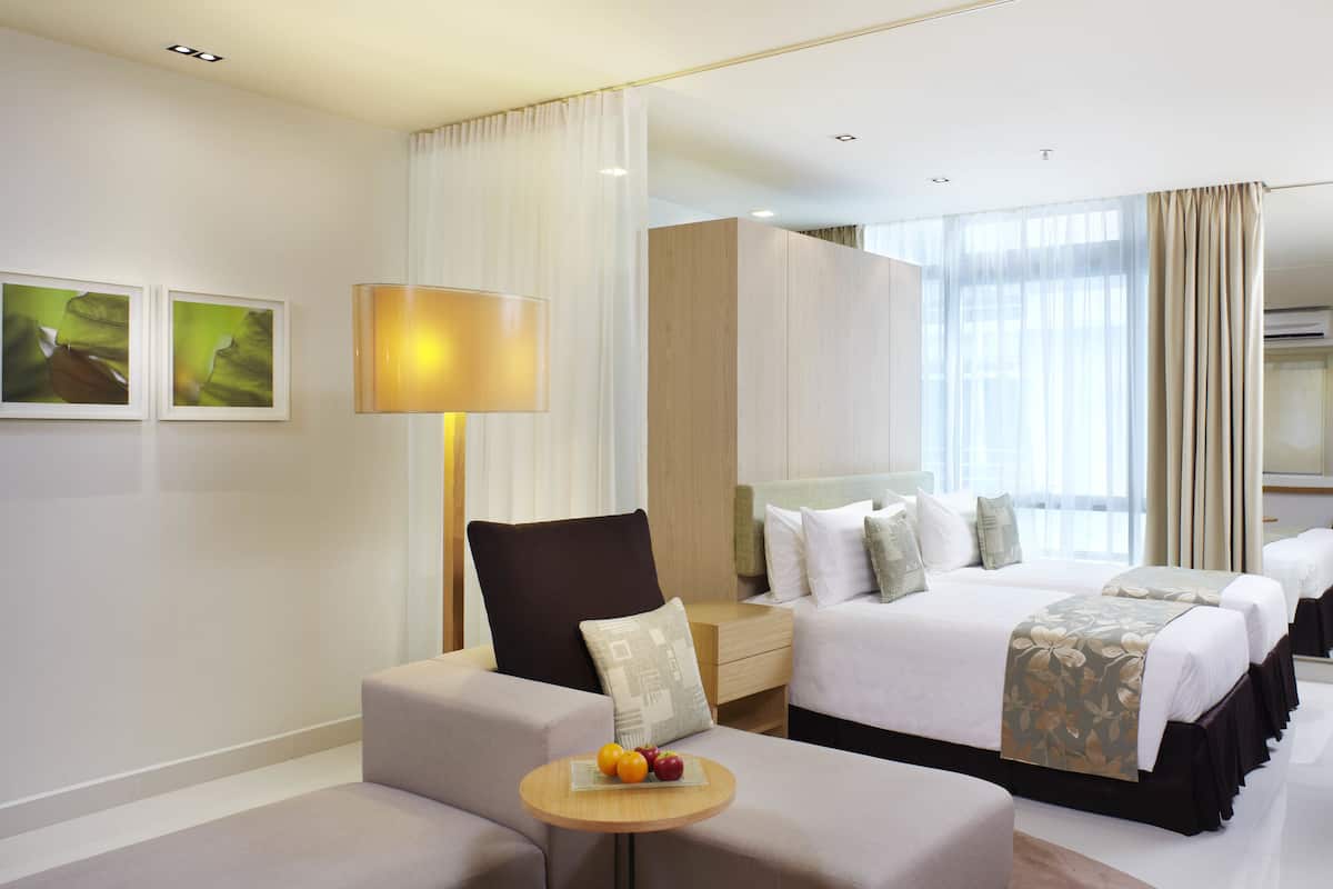 Ein Hotelzimmer mit einem großen Bett, einer Couch, einem kleinen Tisch mit Obst und einer Lampe.
