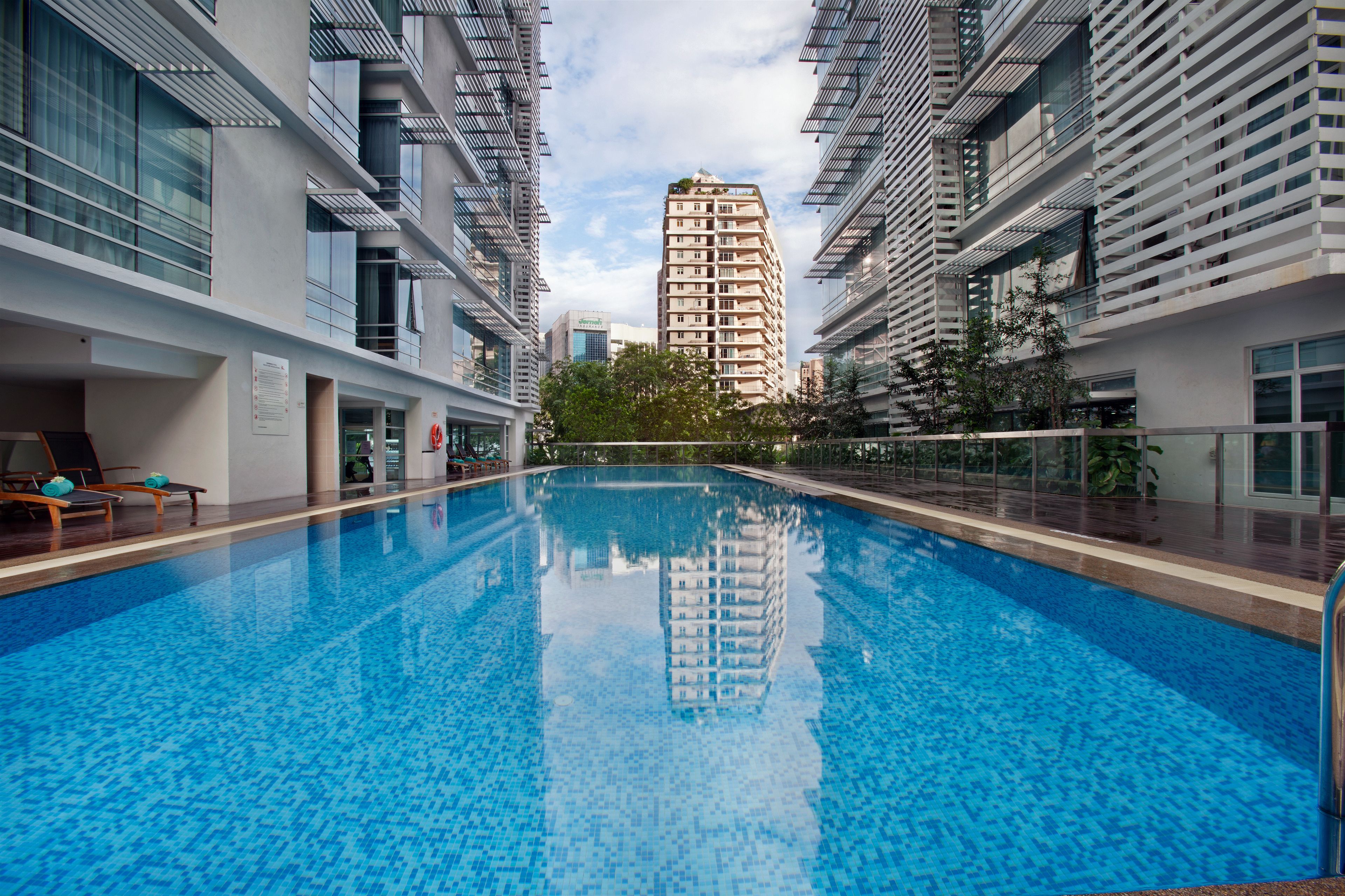 Una piscina con vistas despejadas a edificios modernos cercanos y un rascacielos distante.