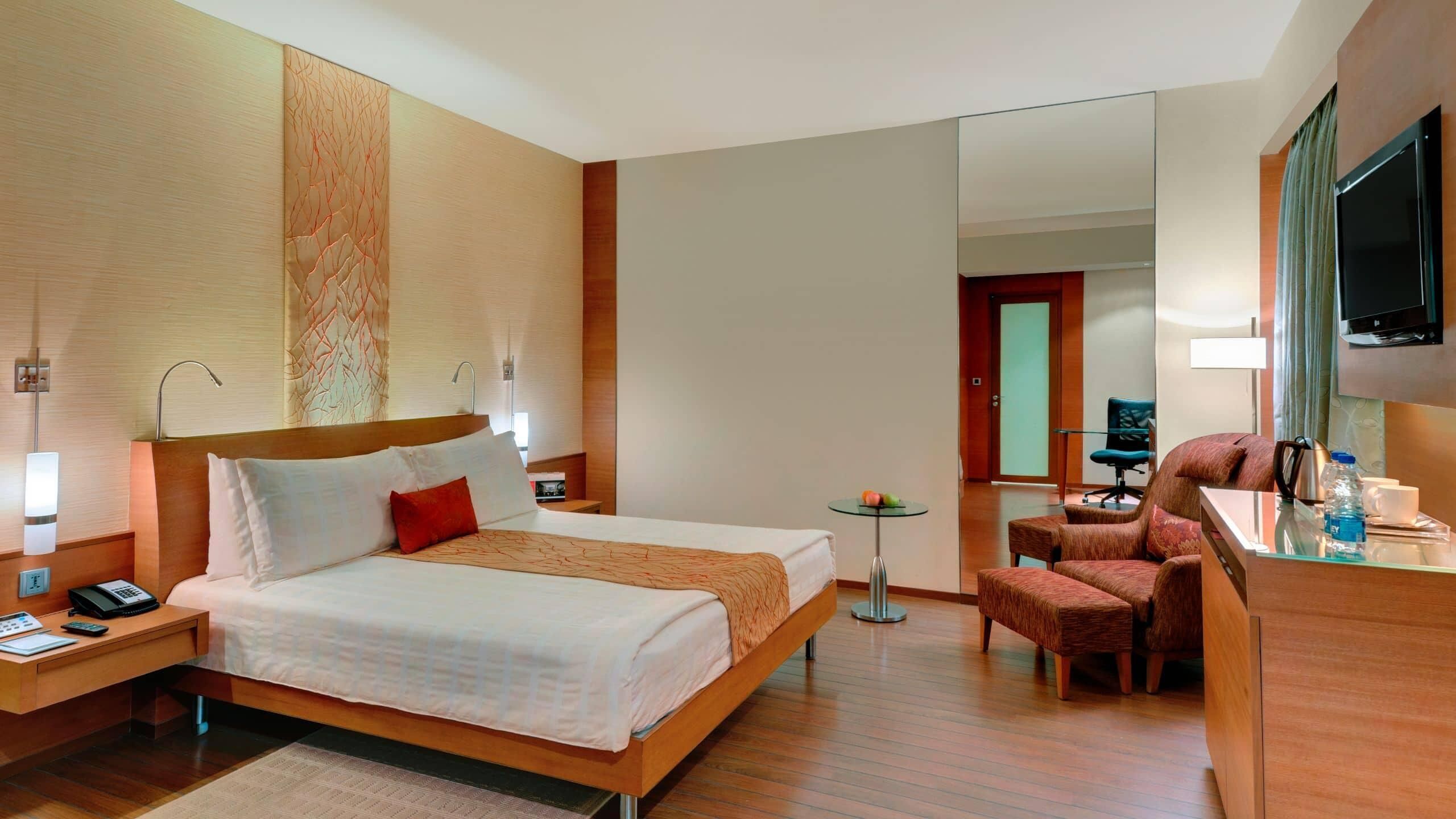Een hotelkamer met een bed, nachtkastje, bureau, stoel en een televisie.