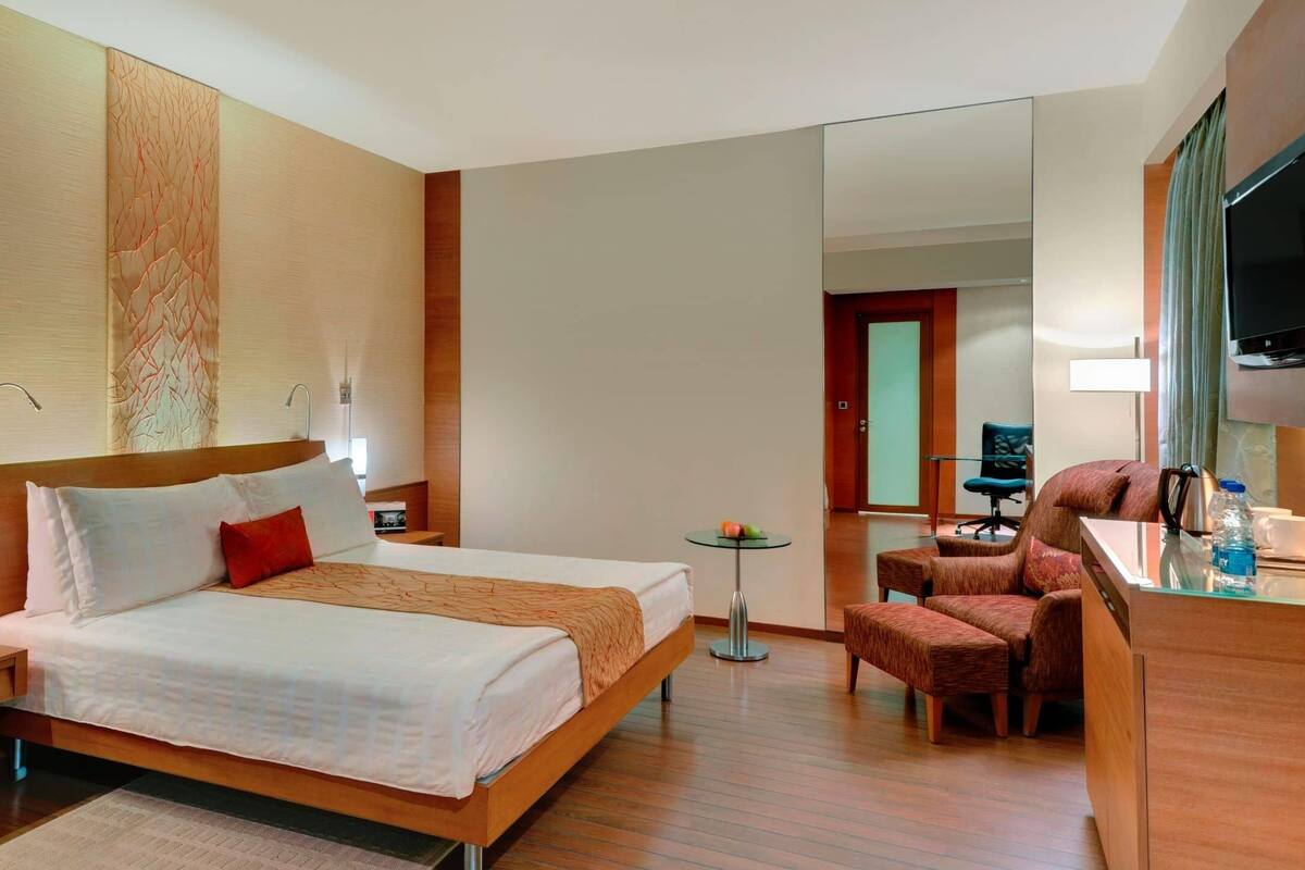 Una habitación de hotel con cama, mesita de noche, escritorio, silla y televisión.