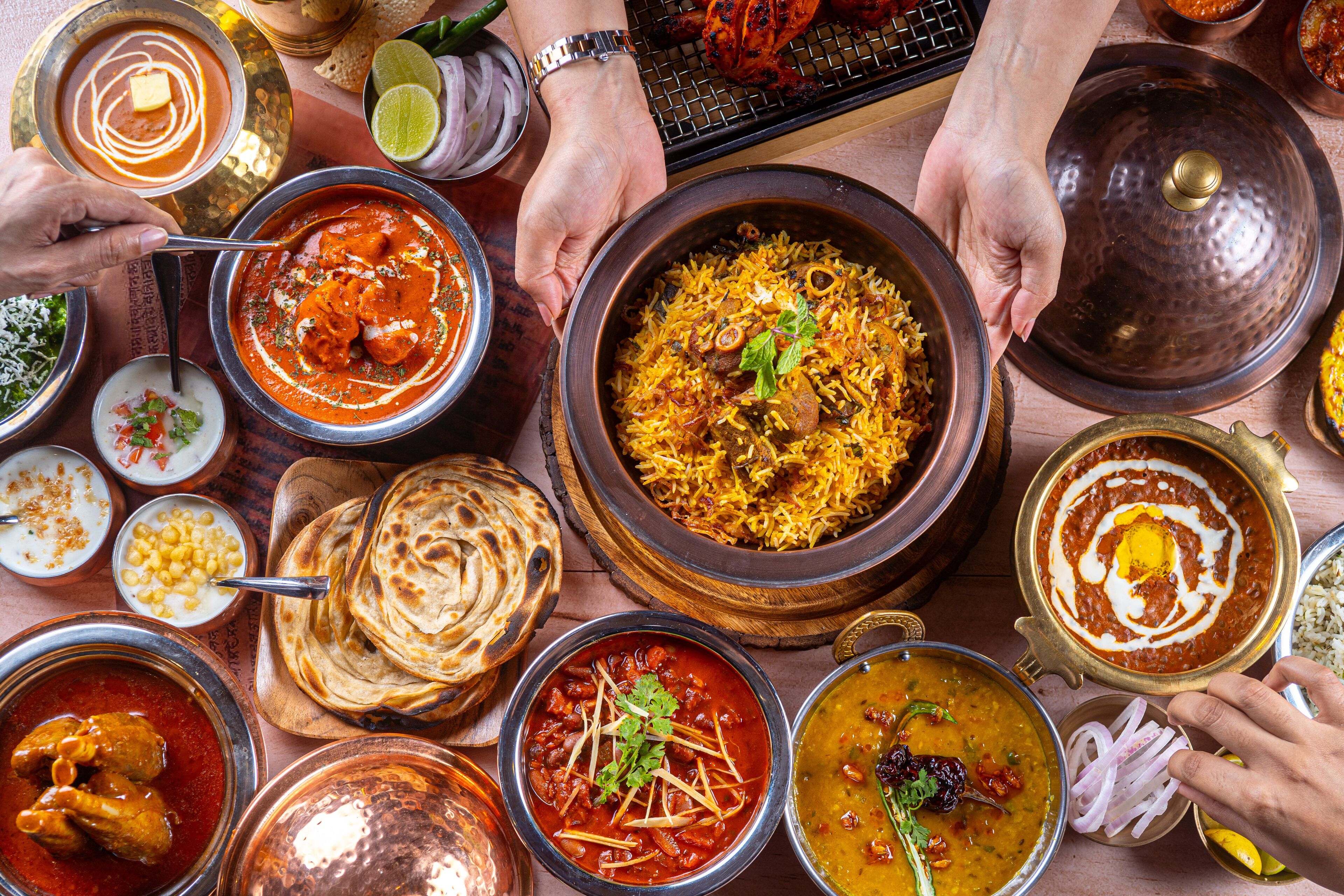 A variety of Indian dishes including curries and rice, served on a wooden table.