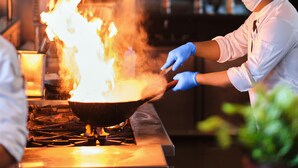 A chef cooking with a wok on a stove in a kitchen. - Hyatt Pune (Pune)