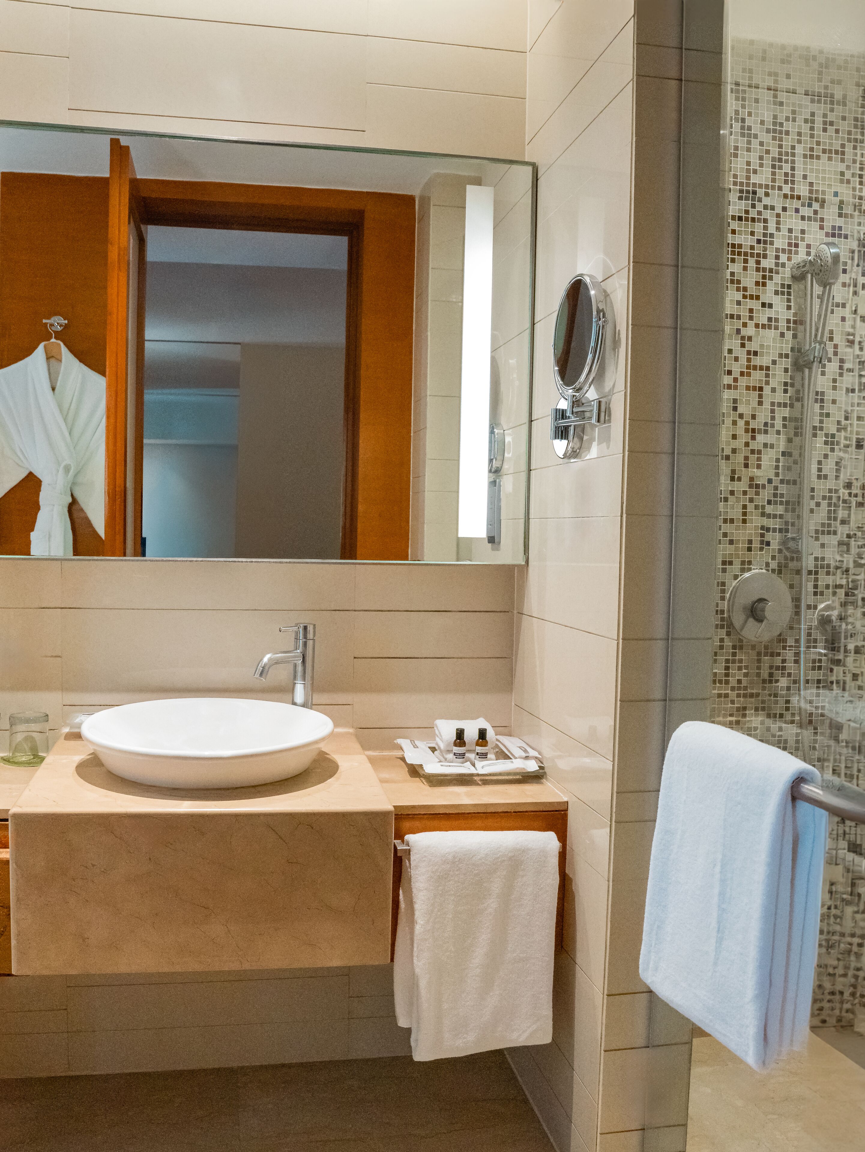 A bathroom with a sink, mirror, and shower.
