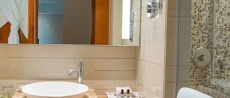 A bathroom with a sink, mirror, and shower.