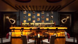 A bar with a central round table and four chairs, surrounded by shelves of bottles and a wall with heart-shaped designs. - Hyatt Pune (Pune)