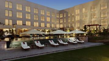 Relax by the pool surrounded by lush greenery and comfortable lounge chairs.