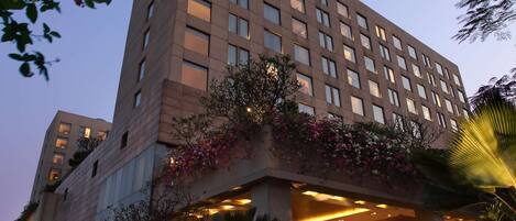 A modern hotel with a flat roof, multiple floors, and a well-lit entrance.