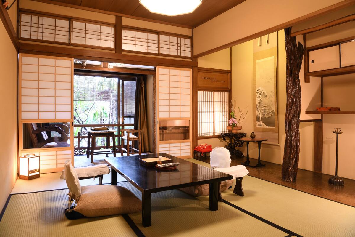 Una habitación japonesa tradicional con suelo de tatami, una mesa baja y puertas correderas shoji.