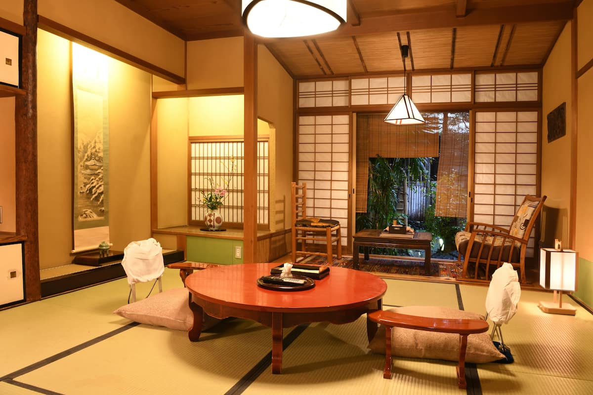 Una habitación japonesa tradicional con suelo de tatami, una mesa de madera baja y puertas correderas.