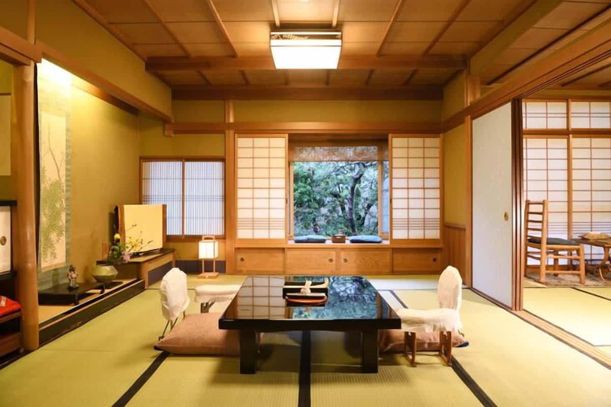Una habitación japonesa tradicional con suelo de tatami, una mesa baja y puertas correderas.