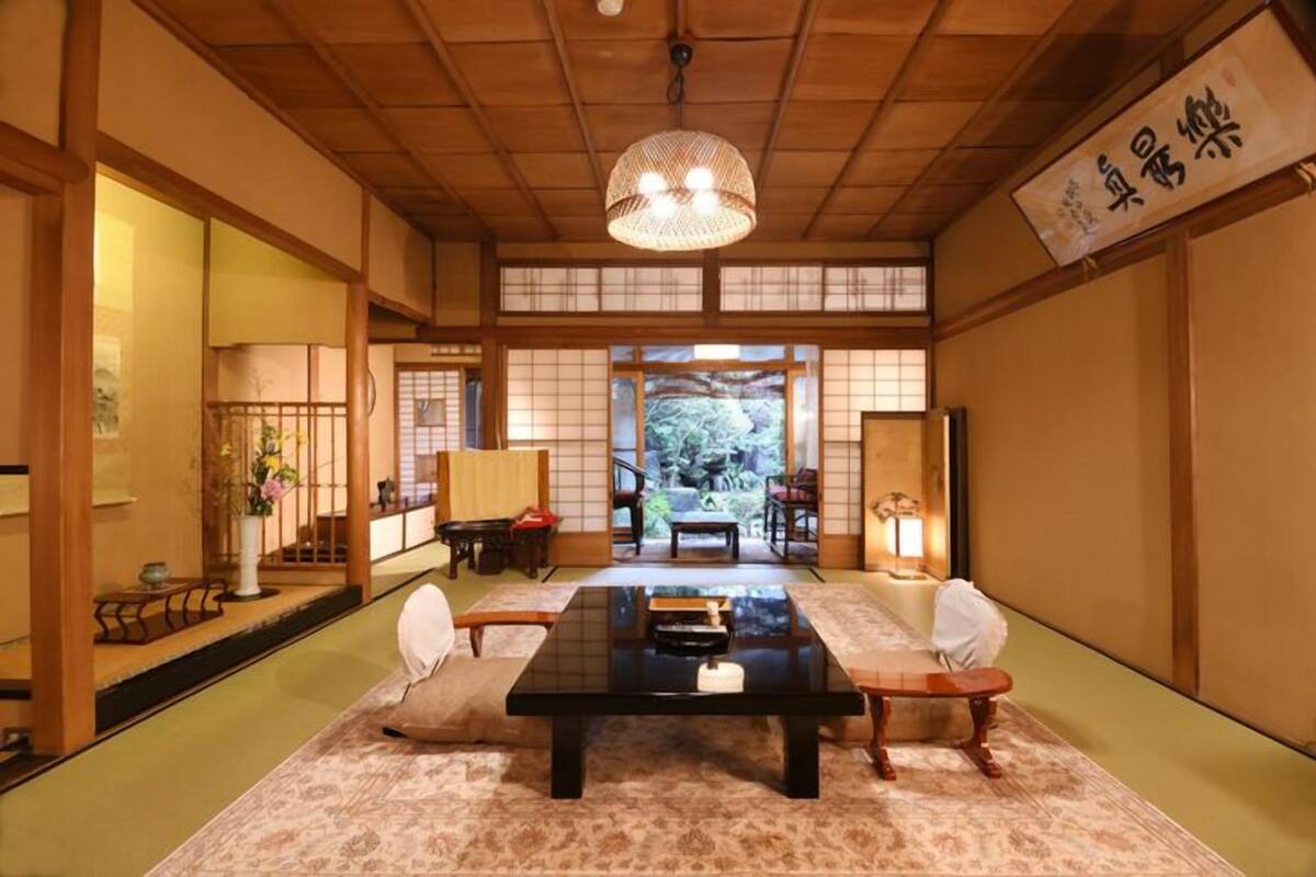 Una habitación japonesa tradicional con suelo de tatami, una mesa baja y puertas correderas que dan a un jardín.