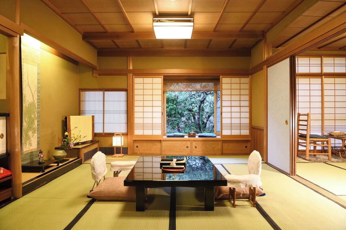 Una habitación japonesa tradicional con suelo de tatami, una mesa baja y biombos shoji.
