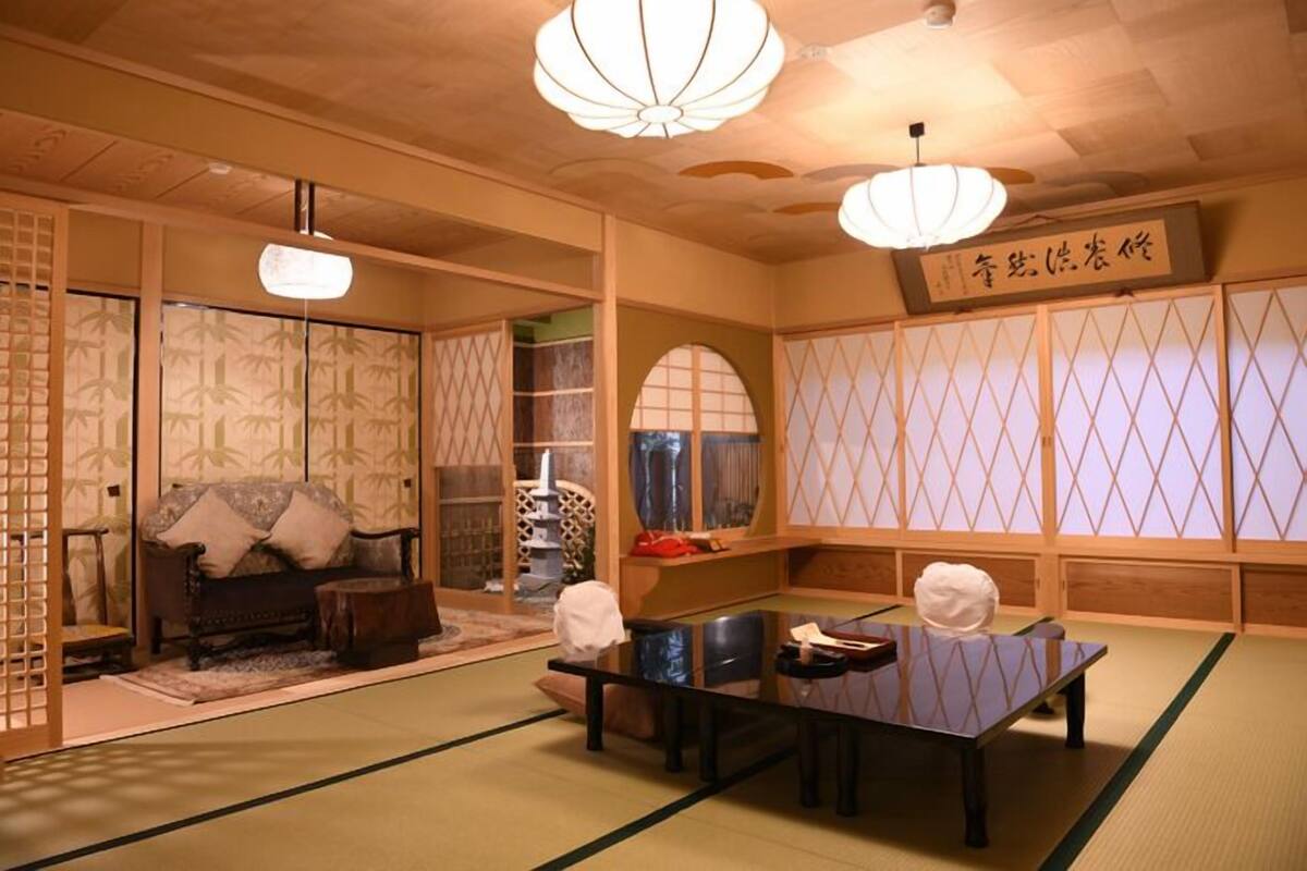 Una habitación tradicional japonesa con suelo de tatami, una mesa baja, cojines y puertas correderas.