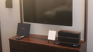 A flat-screen TV mounted on a wall above a wooden dresser.