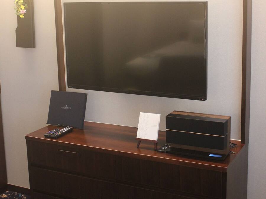A flat-screen TV mounted on a wall above a wooden dresser.