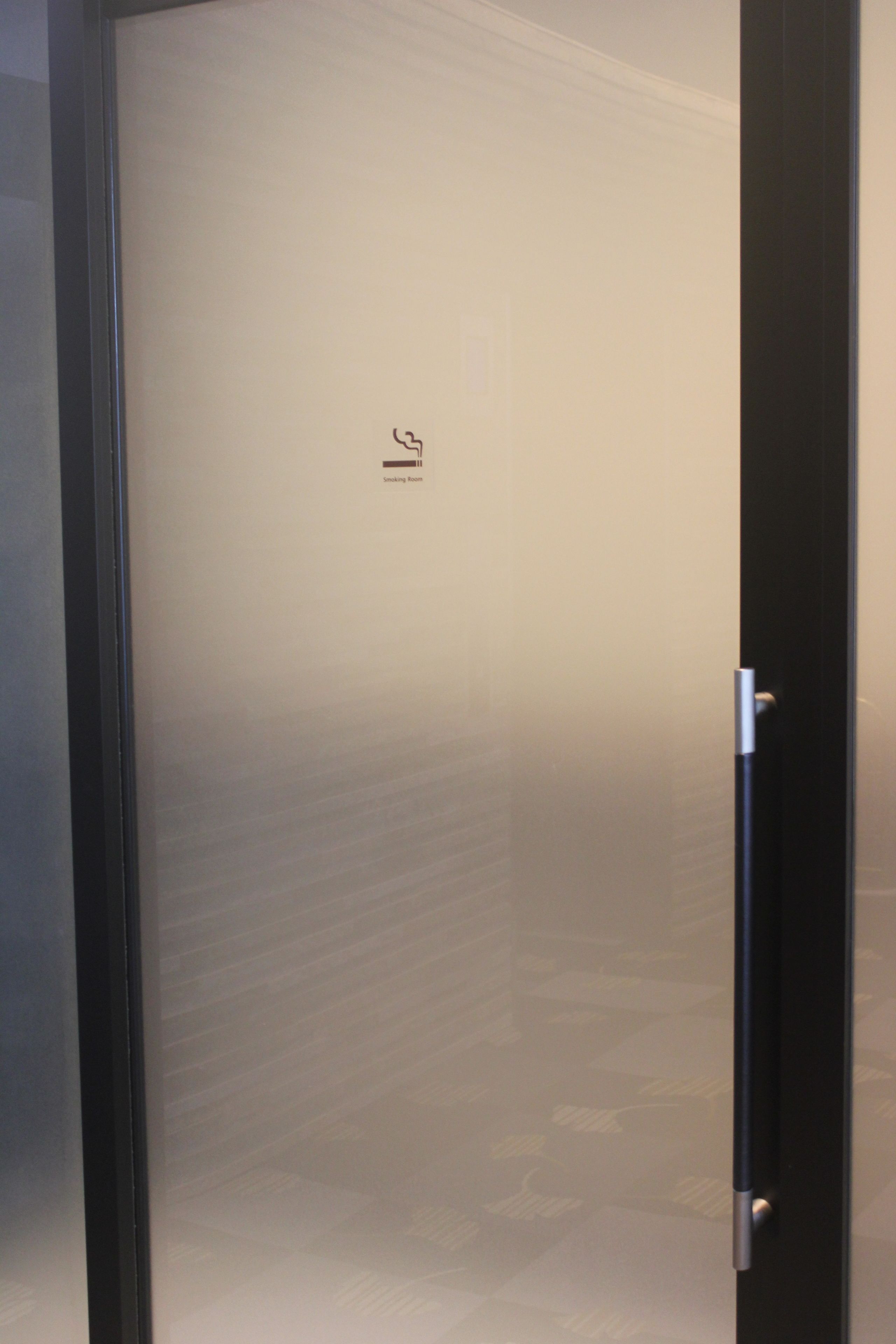 A frosted glass door with a sign indicating a smoking area.