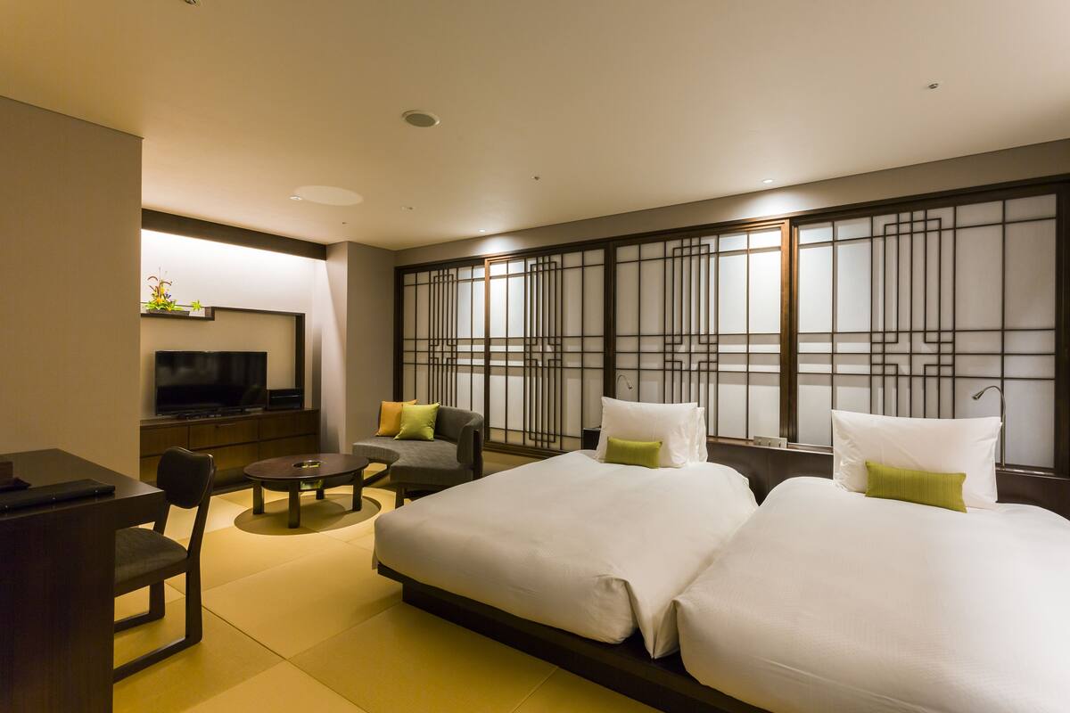 Une chambre d’hôtel avec un grand lit, un bureau, une chaise et un téléviseur.