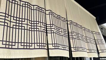 A building facade with a patterned awning and large windows.