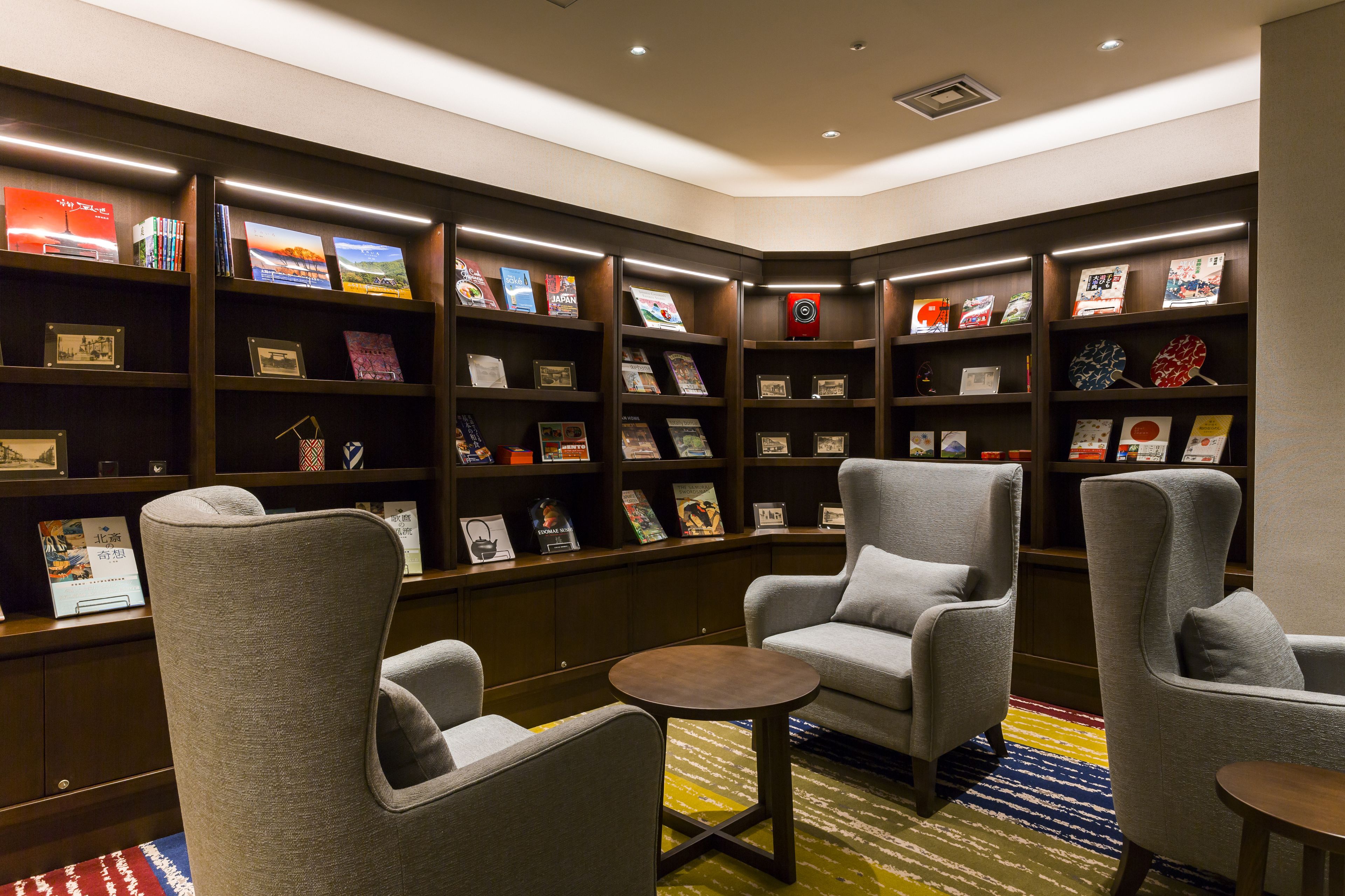A library with bookshelves, comfortable seating, and a small table.