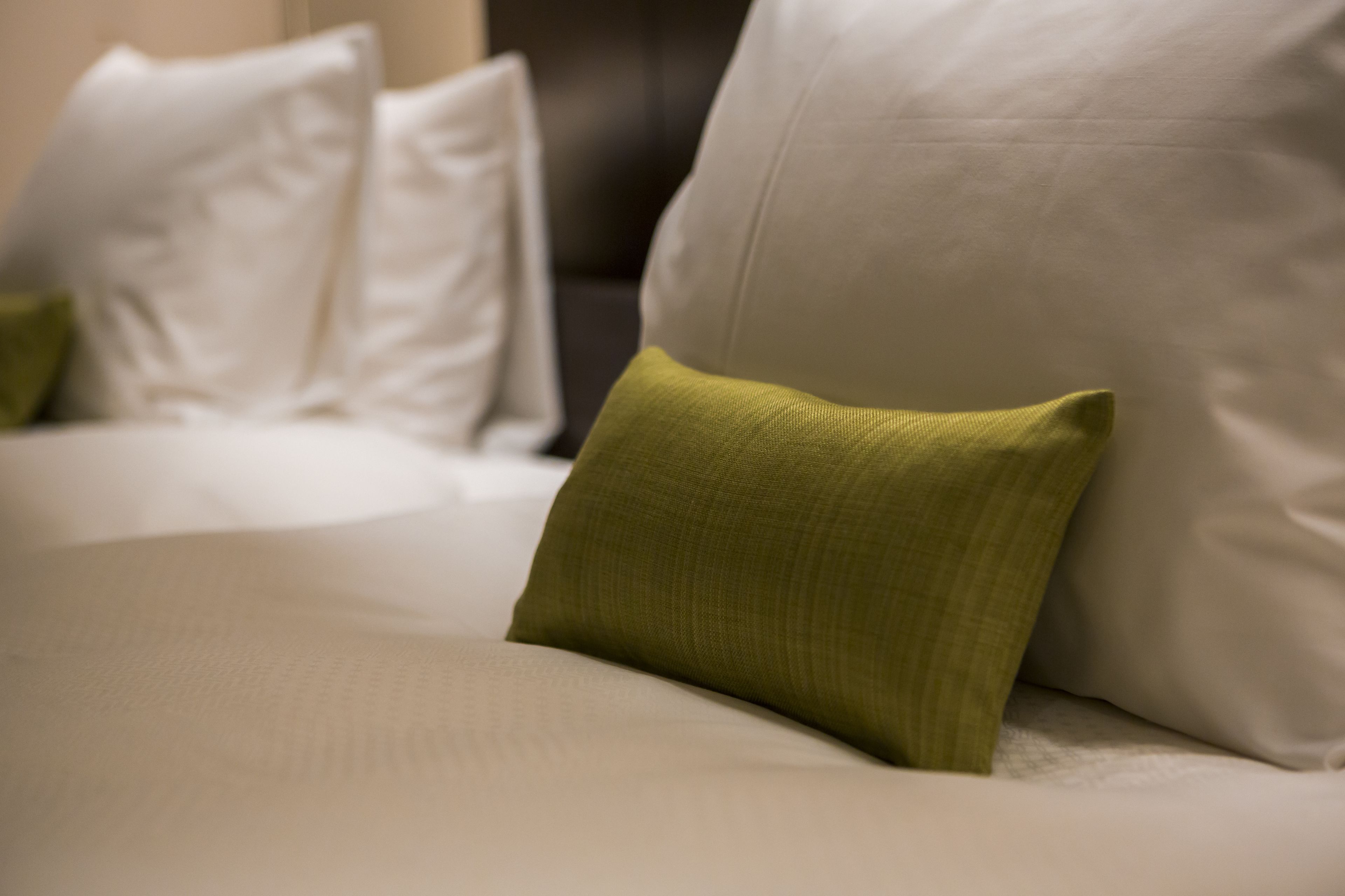 A bed with white and green pillows.