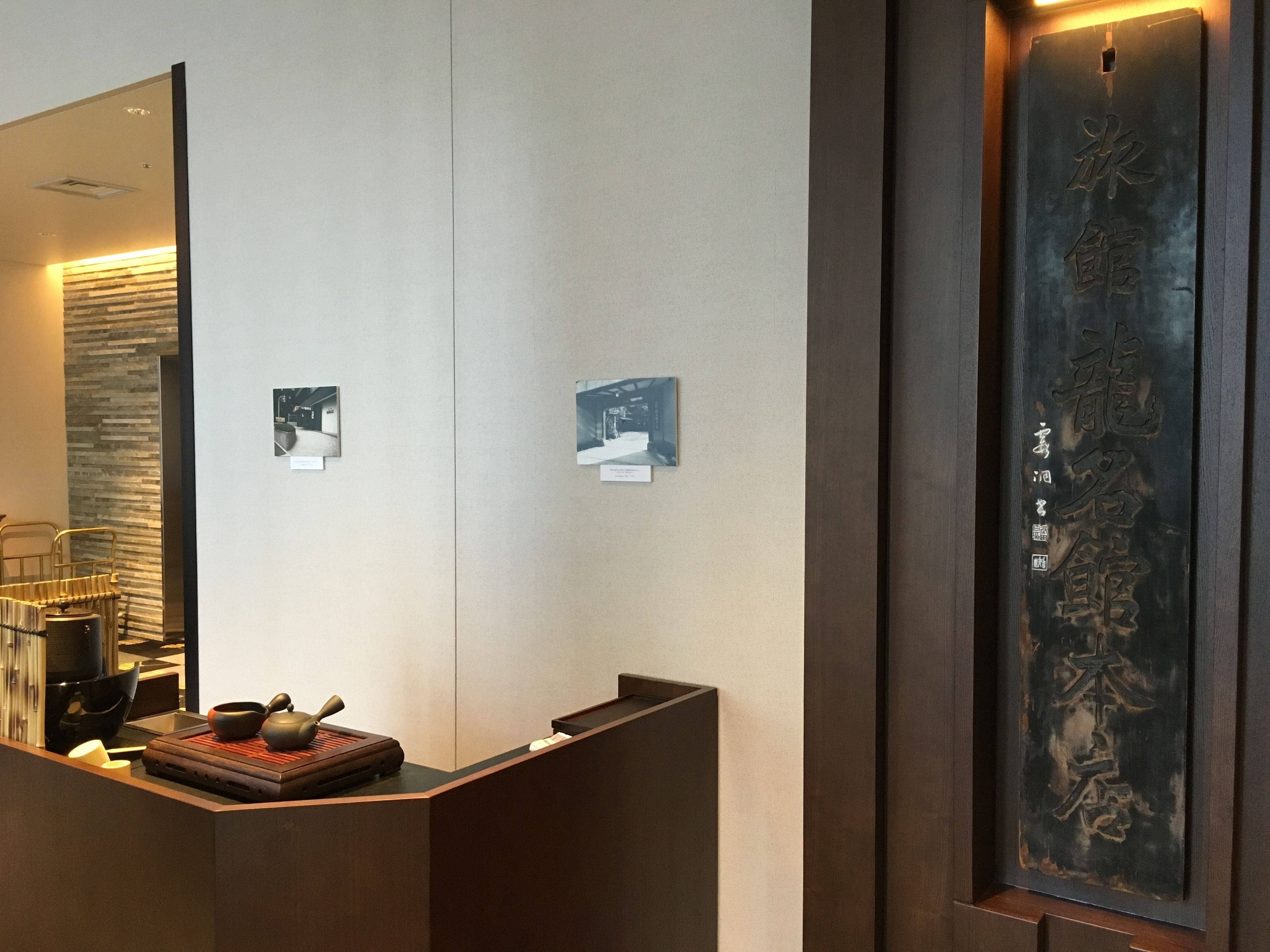 A reception desk with a mirror, a wooden tray with tea utensils, and two framed pictures on the wall.