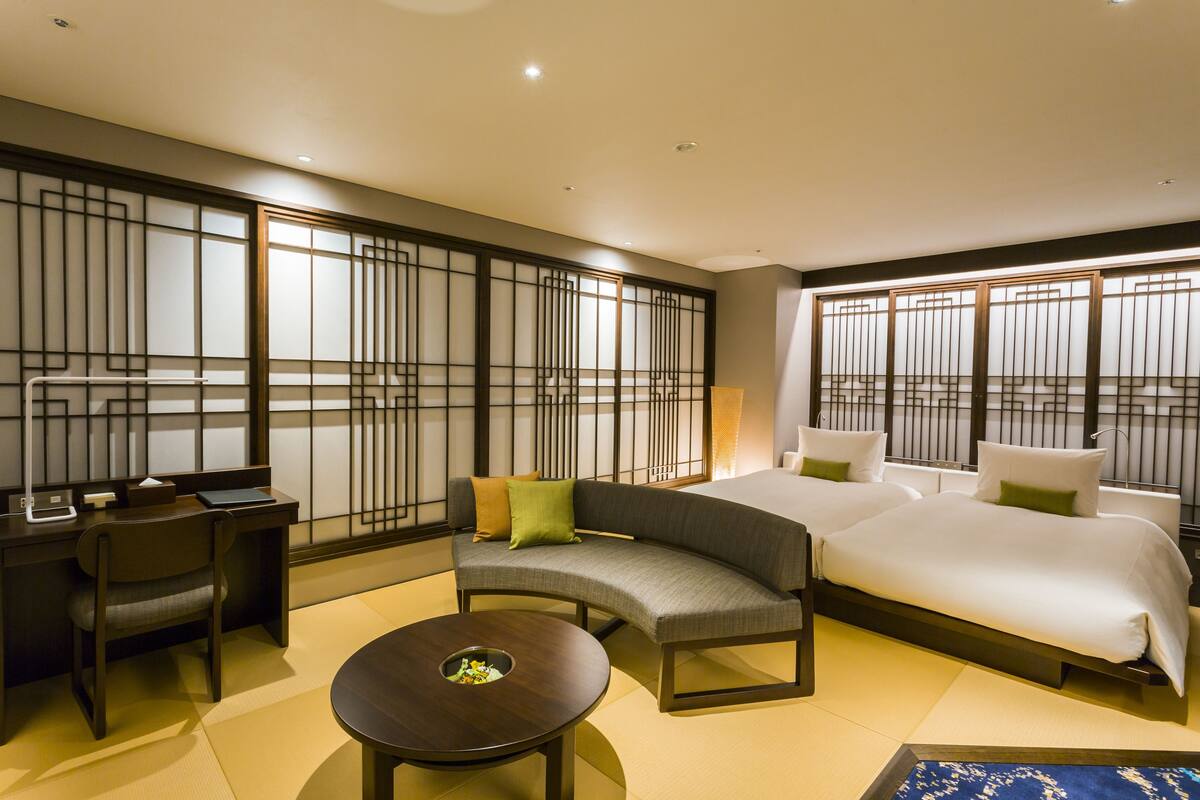 Une chambre d’hôtel avec un canapé, deux lits, un bureau et une petite table.