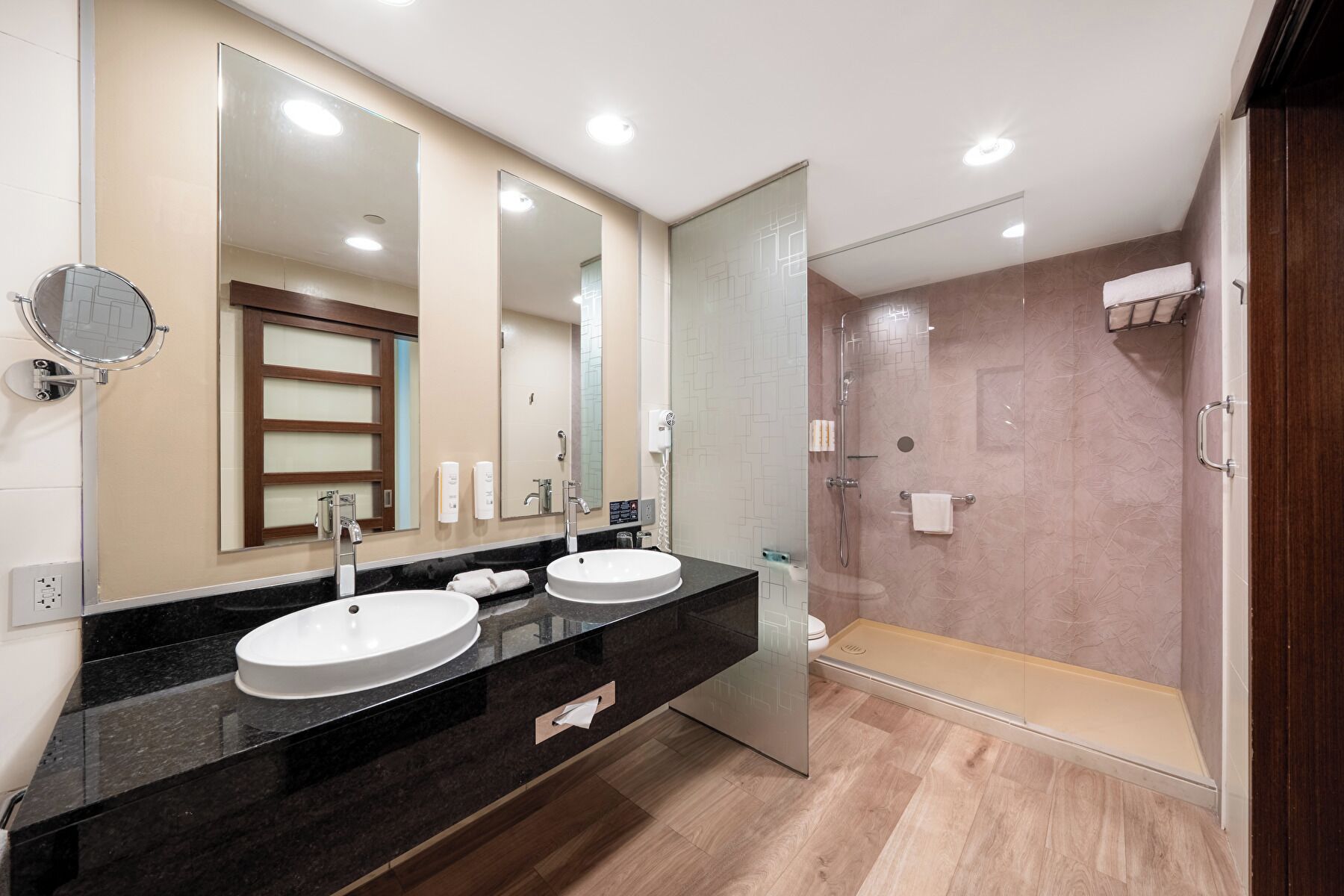 Une salle de bain moderne avec deux lavabos, un grand miroir et une douche à l’italienne.