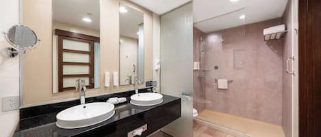 Une salle de bain moderne avec deux lavabos, un grand miroir et une douche à l’italienne.