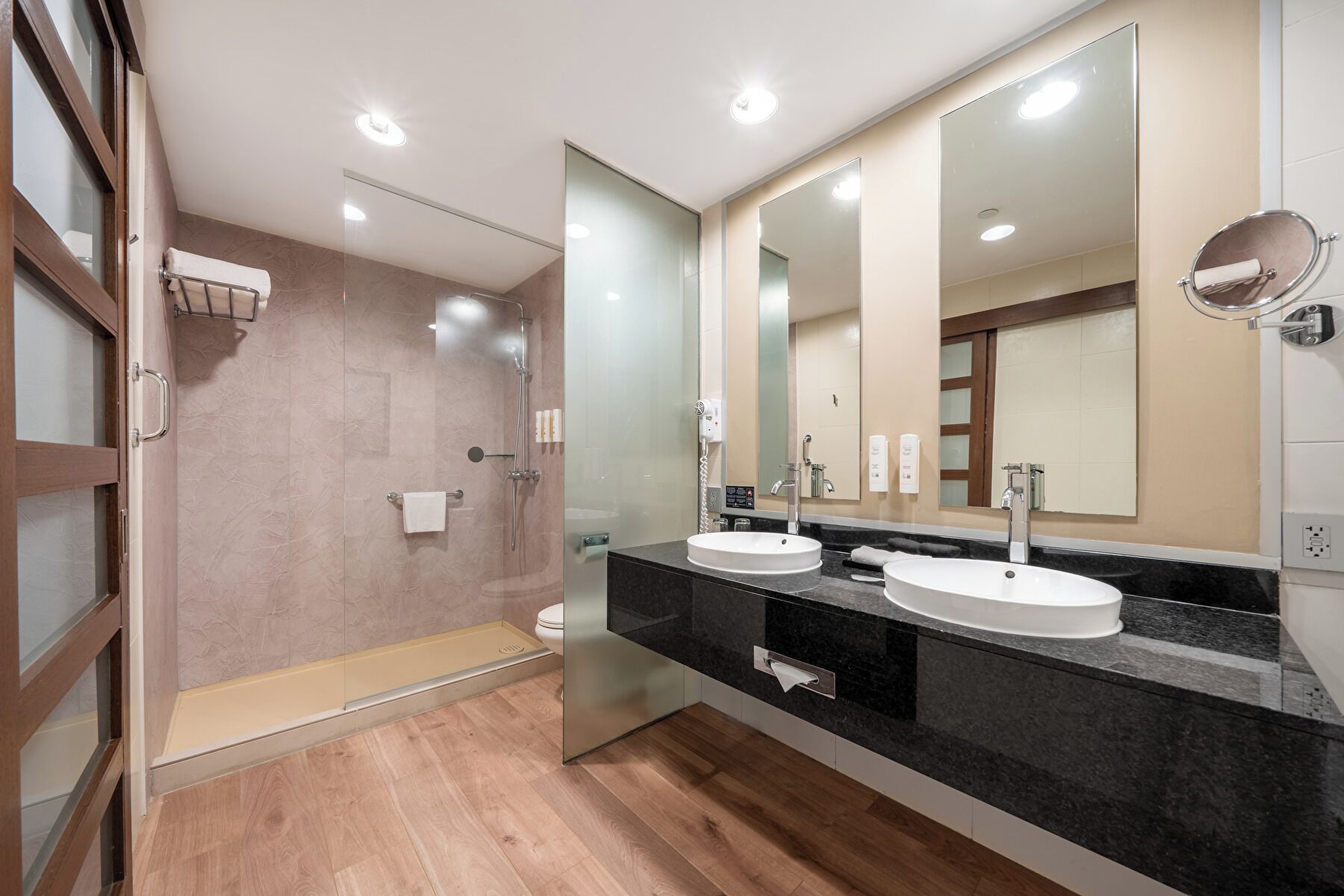 A modern bathroom with a glass shower enclosure, two sinks, and a large mirror.