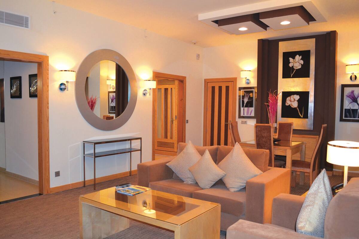 Una habitación de hotel moderna con sofá, mesa de centro y zona de comedor con silla y mesa.