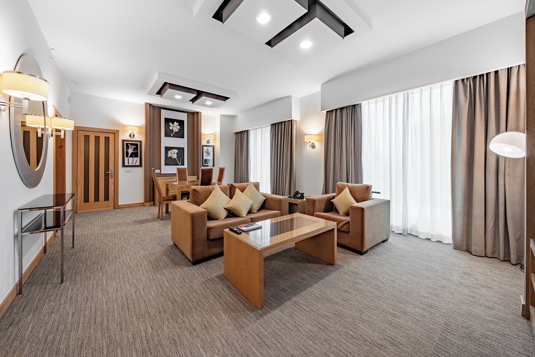 Una habitación de hotel moderna con sala de estar que incluye sofás, una mesa baja y una mesa de comedor.